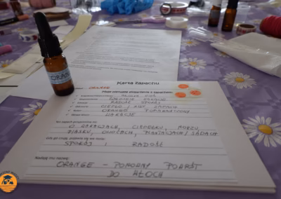 Uczestniczka warsztatów w CAL Jagodno miesza składniki w małej miseczce, tworząc własny olejek zapachowy; na stole leżą buteleczki, pipety i materiały do aromaterapii, a cała scena oddaje spokojną, twórczą atmosferę domowego SPA.