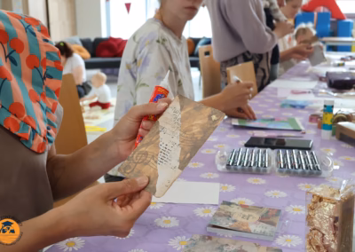 Uczestniczka warsztatów Horyzont Wiedzy przykleja ozdobny papier vintage na kartę afirmacyjną